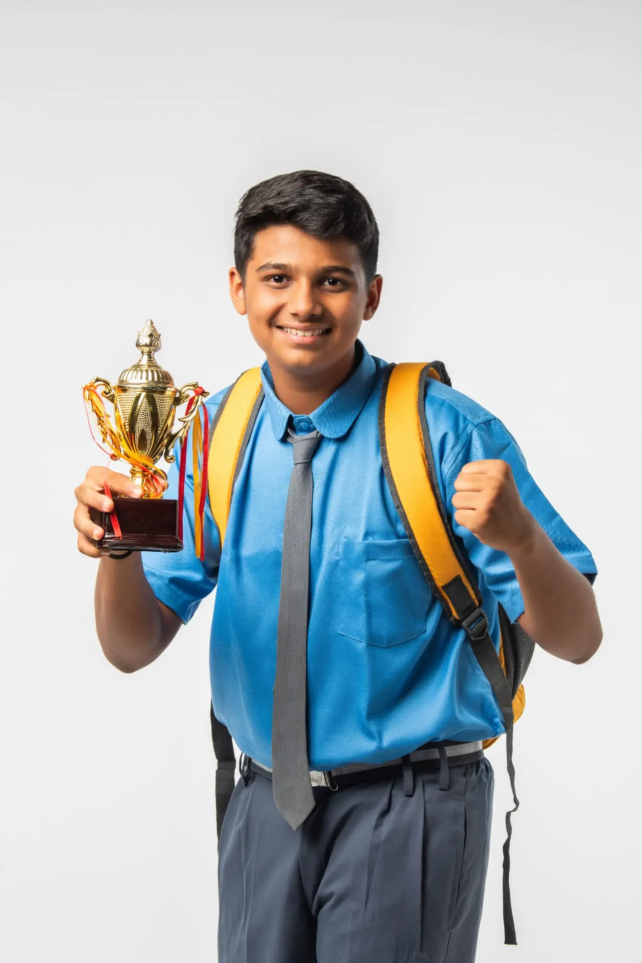 A smiling student in school uniform holding up a trophy